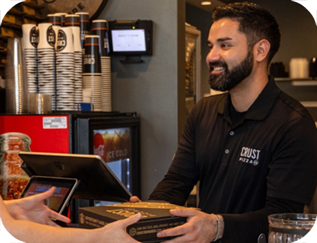 Crust team member handing a pizza box to a guest